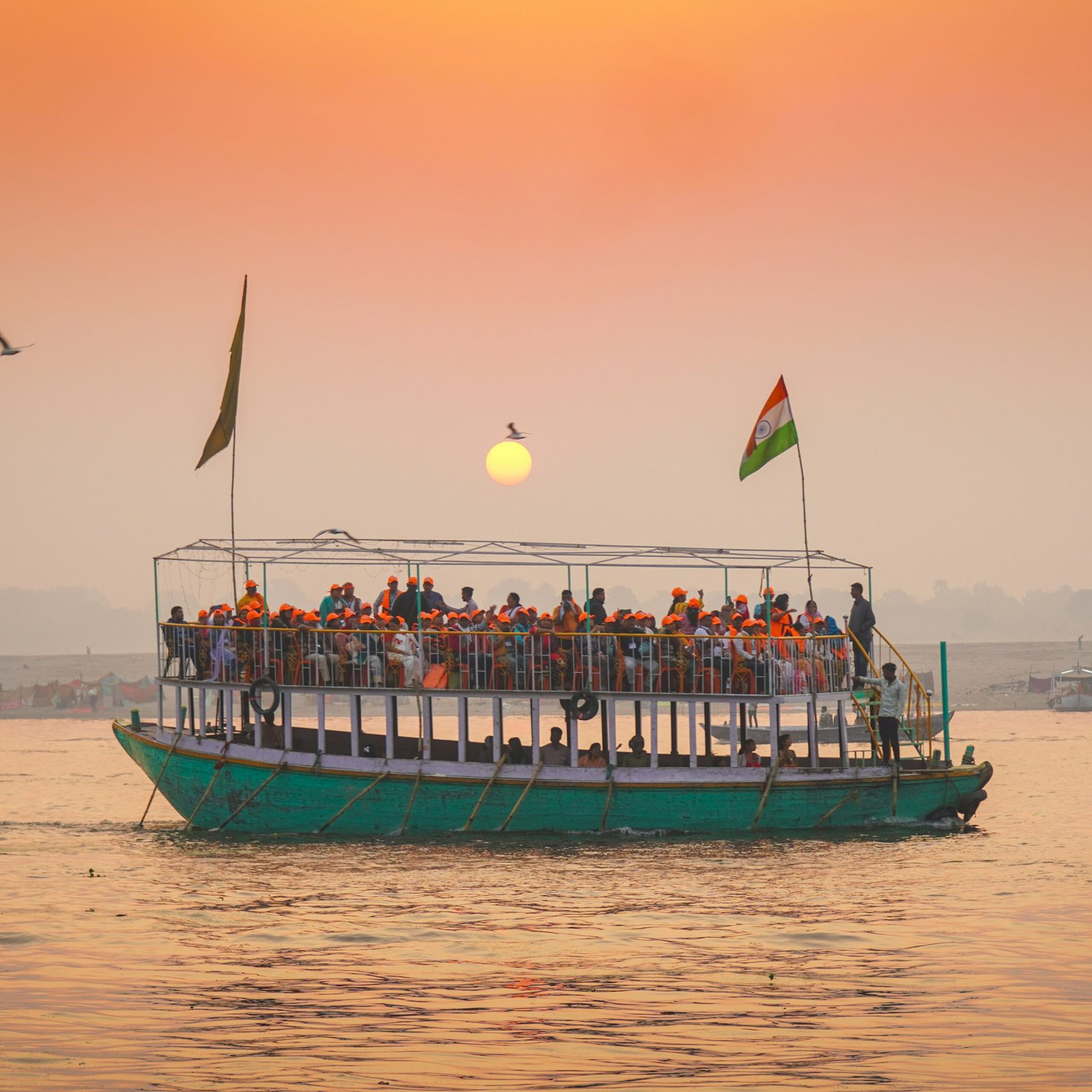 Tour boat filled with people sailing at sunset